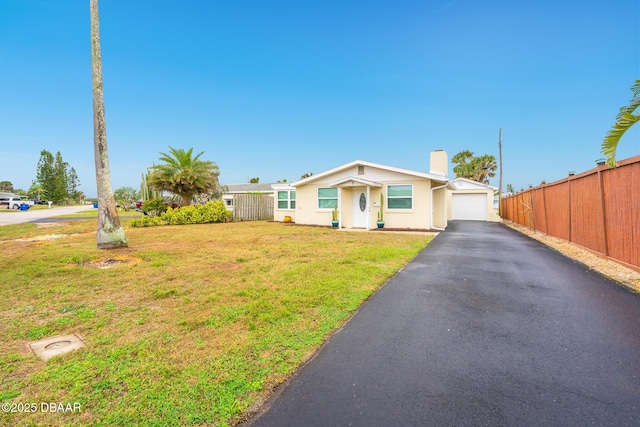 view of front of home with driveway, a chimney, fence, and a front yard