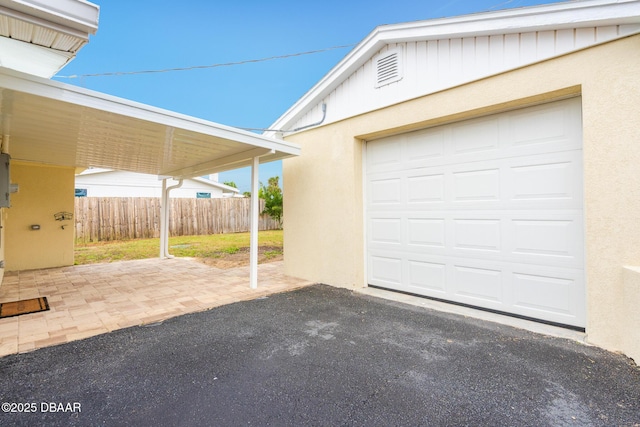 garage featuring fence and aphalt driveway