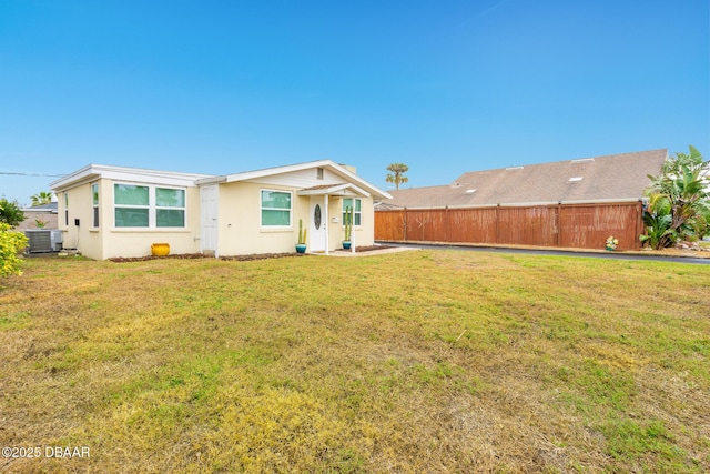 view of front of home with a front lawn, stucco siding, fence, and central air condition unit