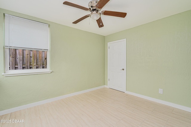 unfurnished room with a ceiling fan and baseboards