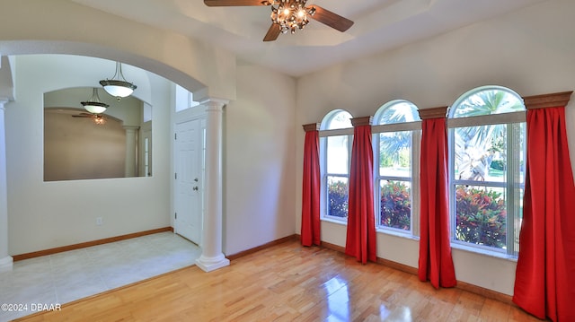 foyer entrance featuring light wood-type flooring, ornate columns, a wealth of natural light, and ceiling fan