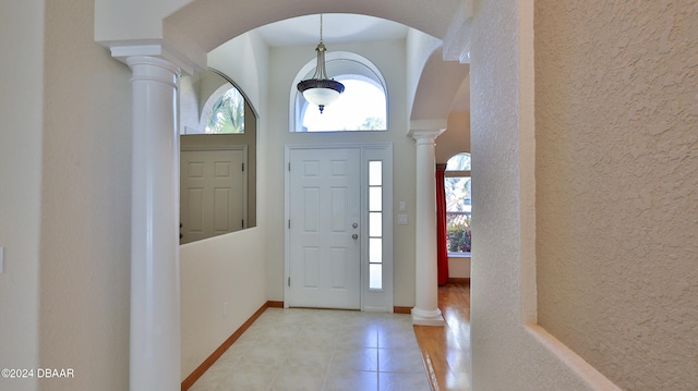 foyer entrance with light wood-type flooring and decorative columns