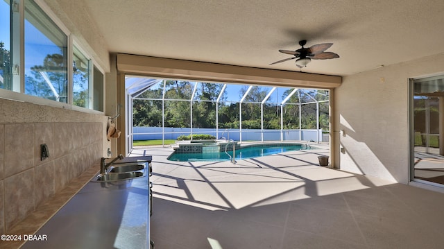 view of pool with glass enclosure, ceiling fan, sink, an in ground hot tub, and a patio