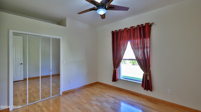 unfurnished bedroom with ceiling fan, a closet, a textured ceiling, and hardwood / wood-style flooring