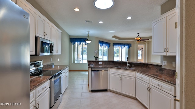 kitchen featuring kitchen peninsula, stainless steel appliances, sink, decorative light fixtures, and white cabinetry