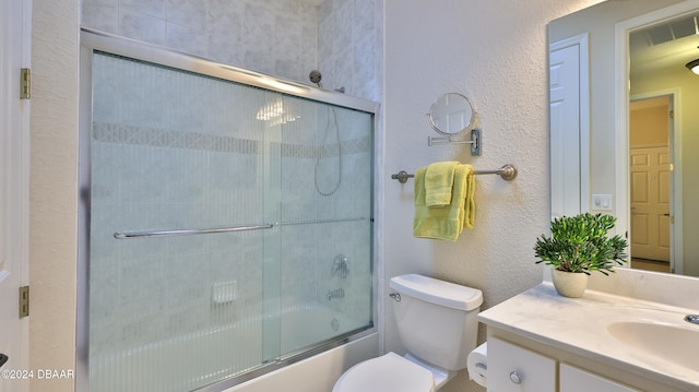 full bathroom featuring vanity, combined bath / shower with glass door, and toilet