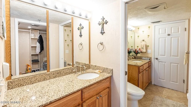 bathroom featuring tile patterned flooring, vanity, a textured ceiling, and toilet