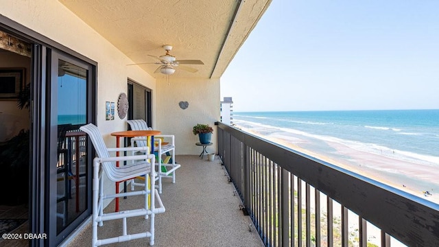 balcony featuring ceiling fan, a water view, and a beach view