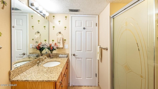 bathroom featuring vanity, a shower with shower door, and a textured ceiling