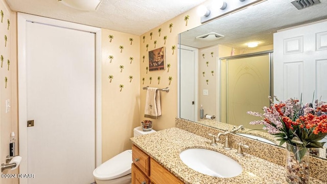 bathroom with vanity, a textured ceiling, toilet, and a shower with shower door