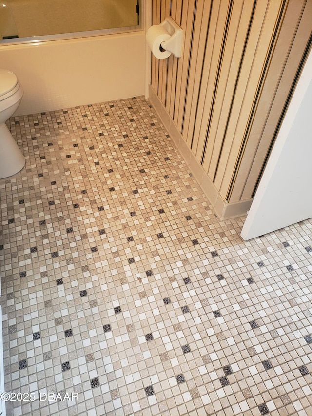 details featuring toilet and combined bath / shower with glass door