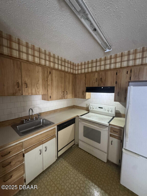 kitchen featuring sink, exhaust hood, a textured ceiling, and white appliances