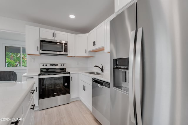 kitchen featuring white cabinets, light wood-type flooring, sink, and appliances with stainless steel finishes