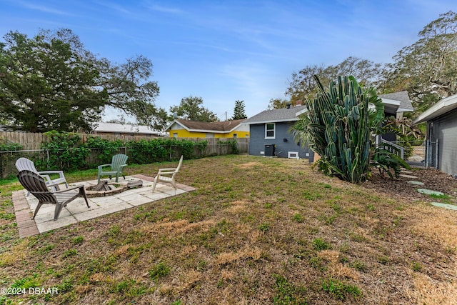 view of yard featuring central AC unit, a patio area, and an outdoor fire pit