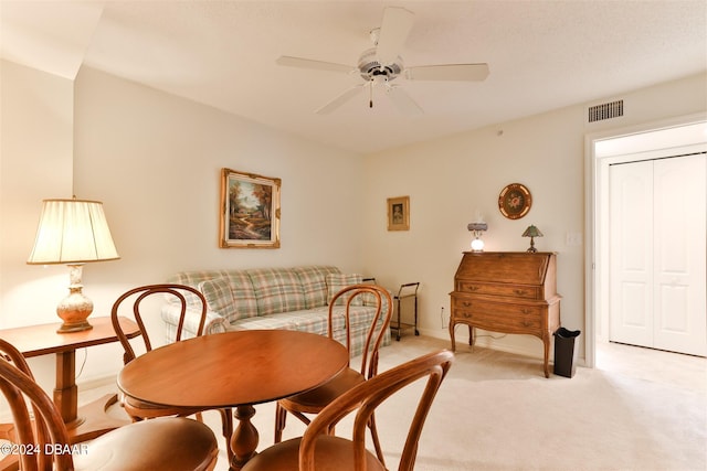 dining room featuring ceiling fan, baseboards, visible vents, and light colored carpet