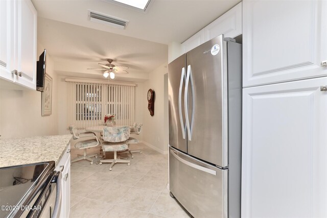 kitchen with light tile patterned floors, visible vents, freestanding refrigerator, white cabinetry, and ceiling fan