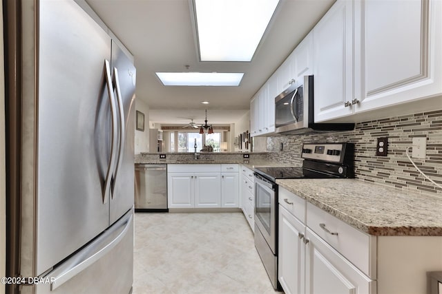 kitchen with light stone counters, a sink, white cabinetry, appliances with stainless steel finishes, and tasteful backsplash