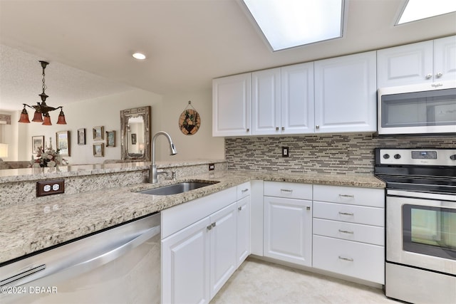 kitchen with stainless steel appliances, a sink, light stone countertops, and decorative backsplash