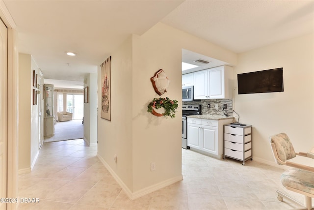 hallway with baseboards, visible vents, and light tile patterned flooring