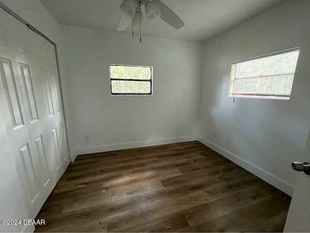 unfurnished bedroom with a closet, dark wood-type flooring, and multiple windows