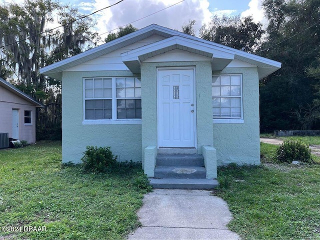 bungalow-style home with a front yard and central AC