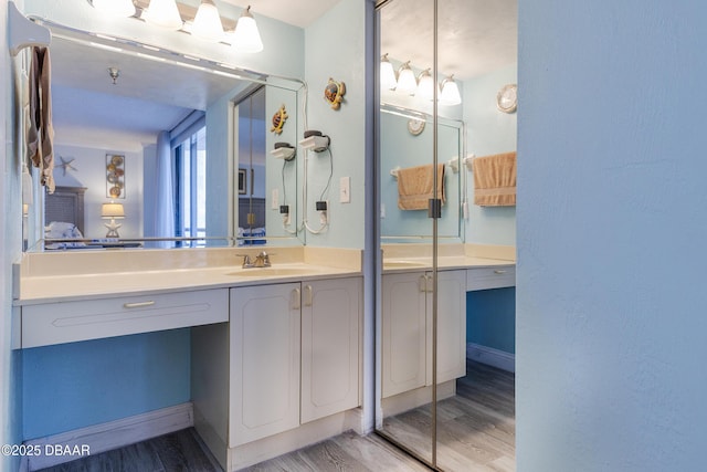 bathroom featuring ensuite bath, wood finished floors, vanity, and baseboards