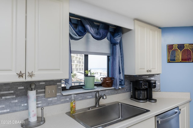 kitchen featuring stainless steel dishwasher, a sink, tasteful backsplash, and white cabinetry