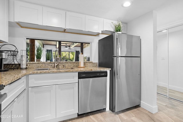 kitchen featuring white cabinetry, sink, stainless steel appliances, and light stone counters