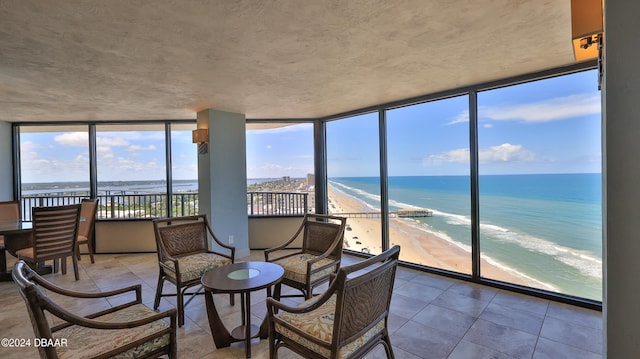 sunroom / solarium featuring a beach view and a water view