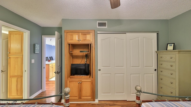 bedroom with ceiling fan, a textured ceiling, a closet, and light wood-type flooring