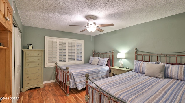 bedroom featuring dark hardwood / wood-style flooring, a closet, a textured ceiling, and ceiling fan