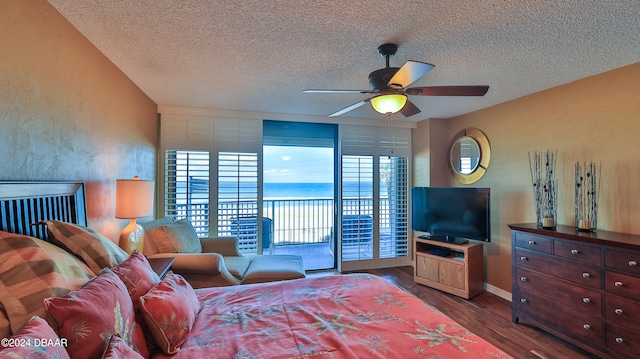 bedroom with access to exterior, a textured ceiling, dark hardwood / wood-style floors, and ceiling fan