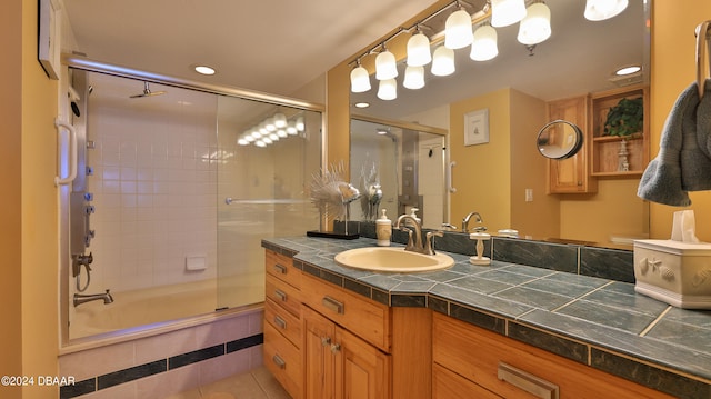 bathroom with bath / shower combo with glass door, vanity, and tile patterned floors