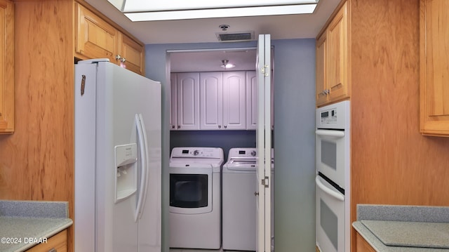 clothes washing area featuring cabinets and washer and clothes dryer