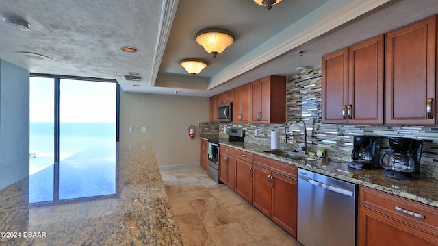 kitchen featuring tasteful backsplash, appliances with stainless steel finishes, light stone countertops, sink, and a water view