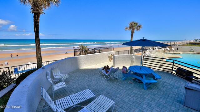 view of patio with a view of the beach, a water view, and a community pool