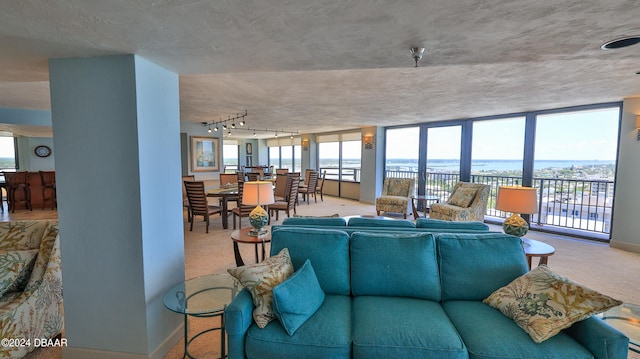 living room featuring expansive windows, a textured ceiling, a water view, and carpet floors