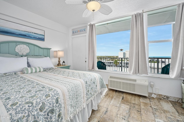 800 N Atlantic Ave Unit 523, Daytona Beach, FL 32118 - bedroom featuring a wall unit AC, wood finished floors, a textured ceiling, ceiling fan, and baseboards