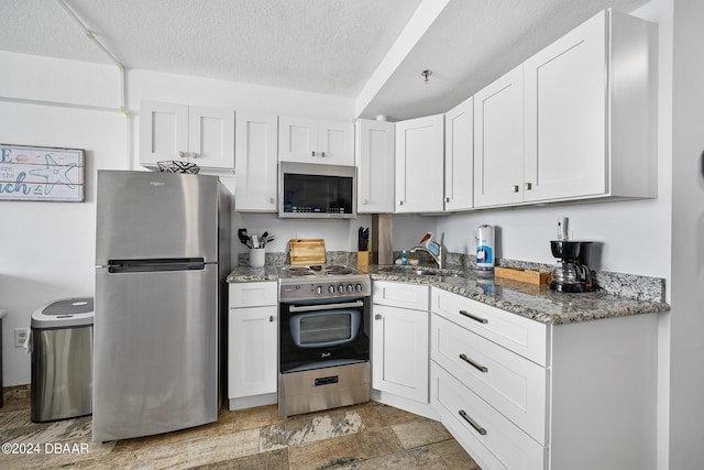 800 N Atlantic Ave Unit 523, Daytona Beach, FL 32118 - kitchen featuring stainless steel appliances, a sink, light stone countertops, a textured ceiling, and white cabinetry
