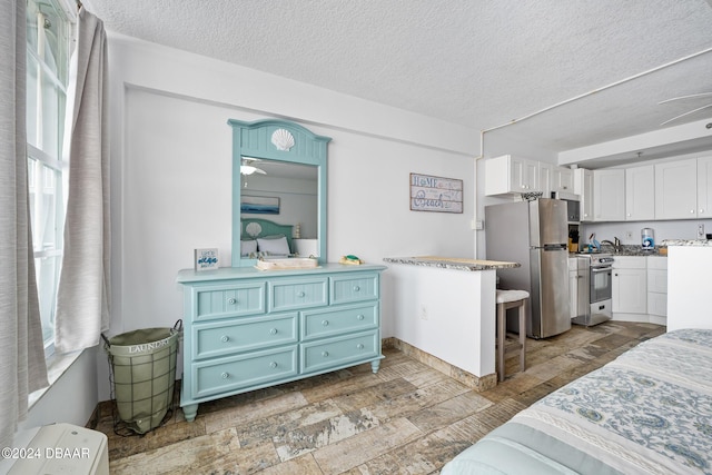 800 N Atlantic Ave Unit 523, Daytona Beach, FL 32118 - bedroom featuring freestanding refrigerator, a textured ceiling, and stone finish floors