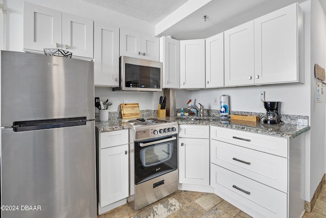 800 N Atlantic Ave Unit 523, Daytona Beach, FL 32118 - kitchen featuring appliances with stainless steel finishes, a sink, light stone counters, a textured ceiling, and white cabinets