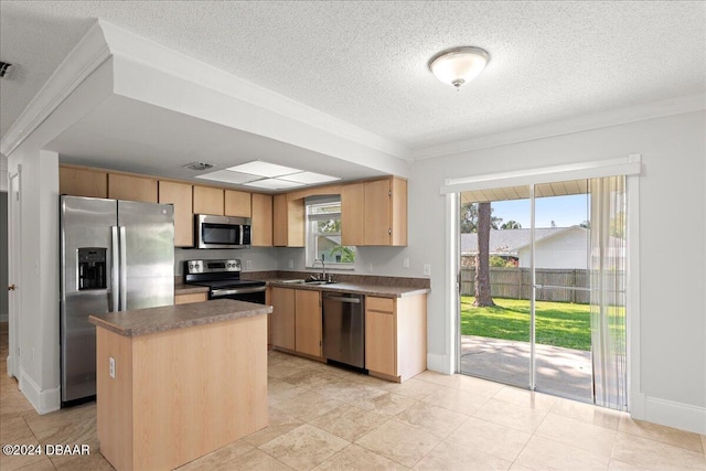 kitchen featuring appliances with stainless steel finishes, sink, a kitchen island, and plenty of natural light