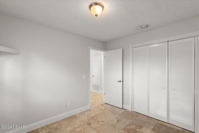 unfurnished bedroom with a textured ceiling and a closet