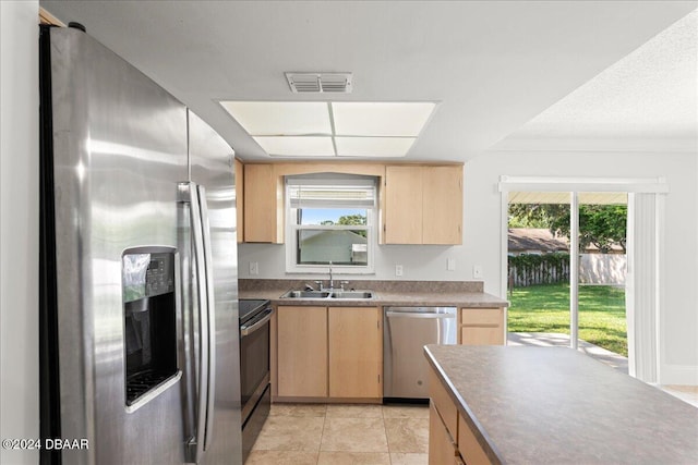 kitchen with stainless steel appliances, light tile patterned flooring, plenty of natural light, and sink