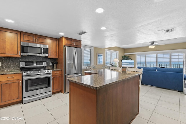 815 Ocean Shore Blvd Unit U1B, Ormond Beach, FL 32176 - kitchen with appliances with stainless steel finishes, light tile patterned flooring, brown cabinetry, healthy amount of natural light, and recessed lighting
