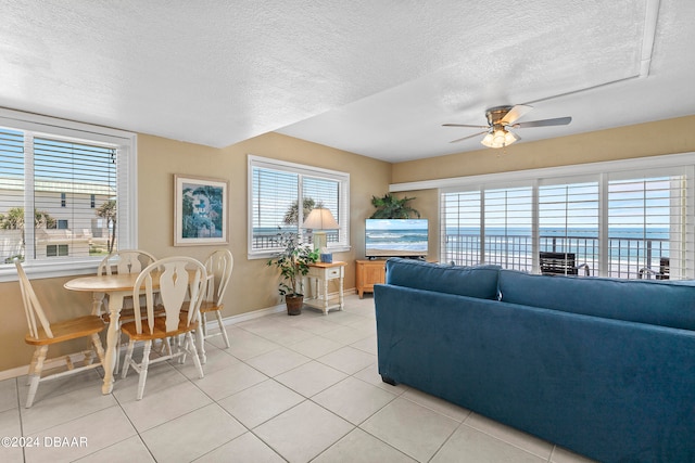 living room with ceiling fan, a textured ceiling, and light tile patterned floors