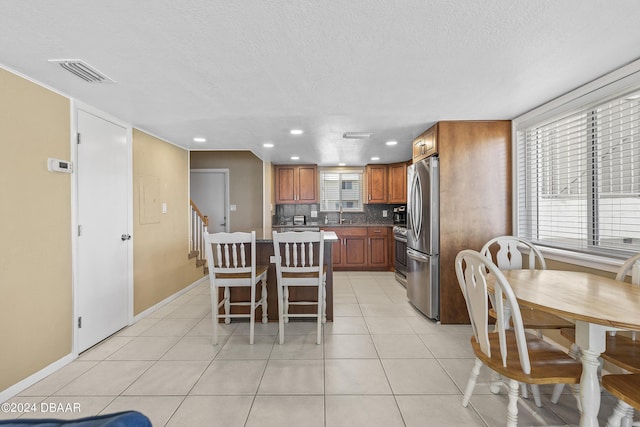 815 Ocean Shore Blvd Unit U1B, Ormond Beach, FL 32176 - kitchen with appliances with stainless steel finishes, a textured ceiling, backsplash, brown cabinetry, and a kitchen island