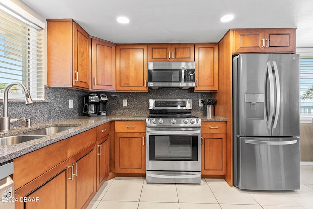 kitchen with stainless steel appliances, sink, tasteful backsplash, dark stone counters, and light tile patterned floors