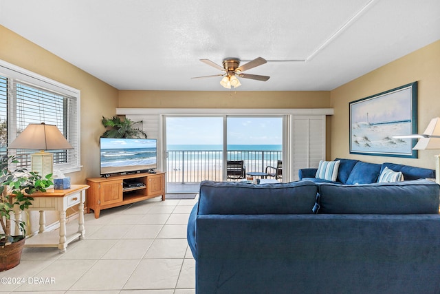 living room featuring ceiling fan, a textured ceiling, and light tile patterned flooring