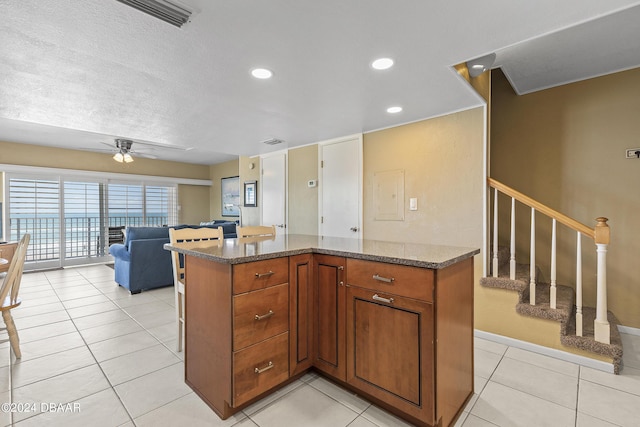 815 Ocean Shore Blvd Unit U1B, Ormond Beach, FL 32176 - kitchen featuring a ceiling fan, brown cabinetry, baseboards, dark stone countertops, and open floor plan